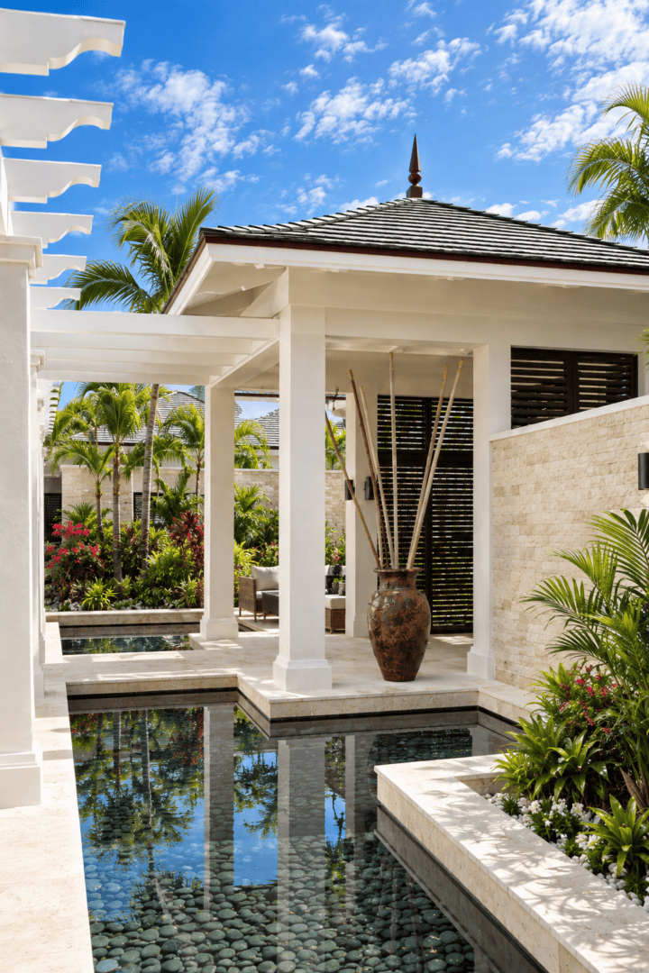 Elegant Bahamas villa with pool, lush greenery, and tropical sky.