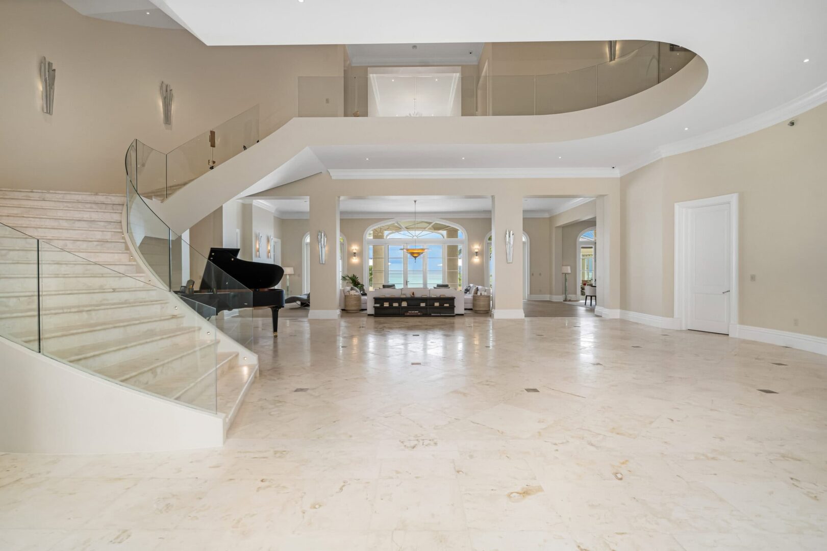 Spacious hotel lobby with grand staircase and elegant decor.