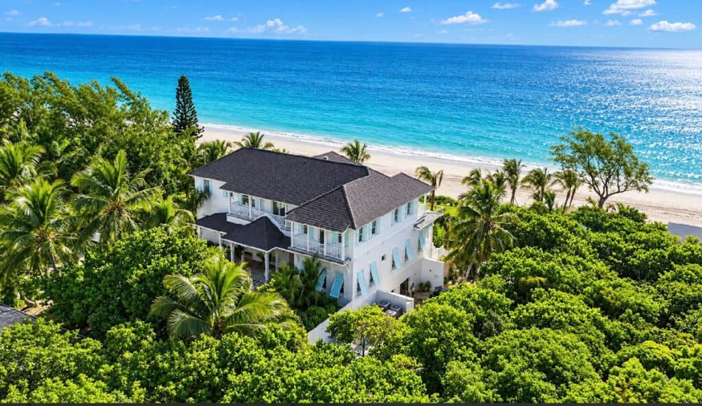 Elegant beachfront villa surrounded by lush greenery and ocean views in Bahamas.