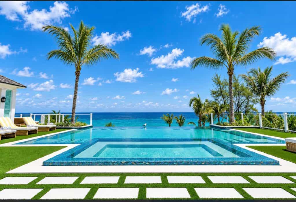 Beautiful beachfront pool with palm trees and ocean view in Bahamas.