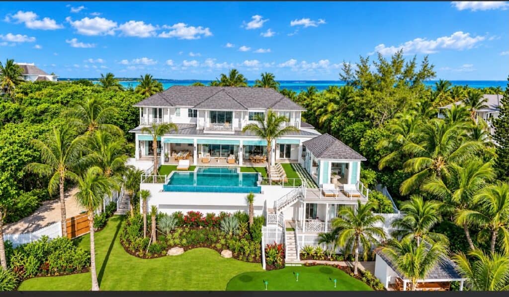 Stunning beachfront villa with pool, lush gardens, and ocean view in Bahamas.