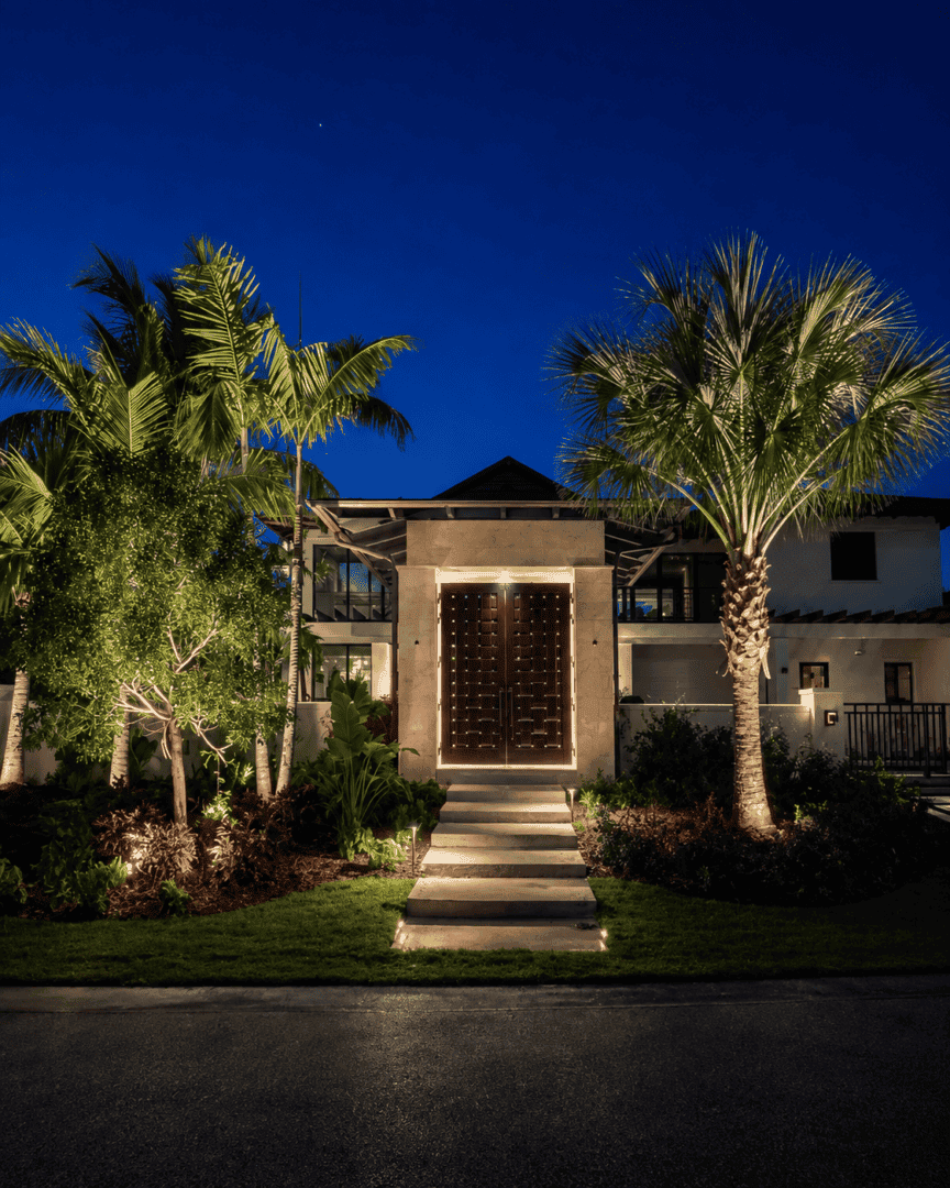 Elegant modern house with palm trees and landscaped garden at night.