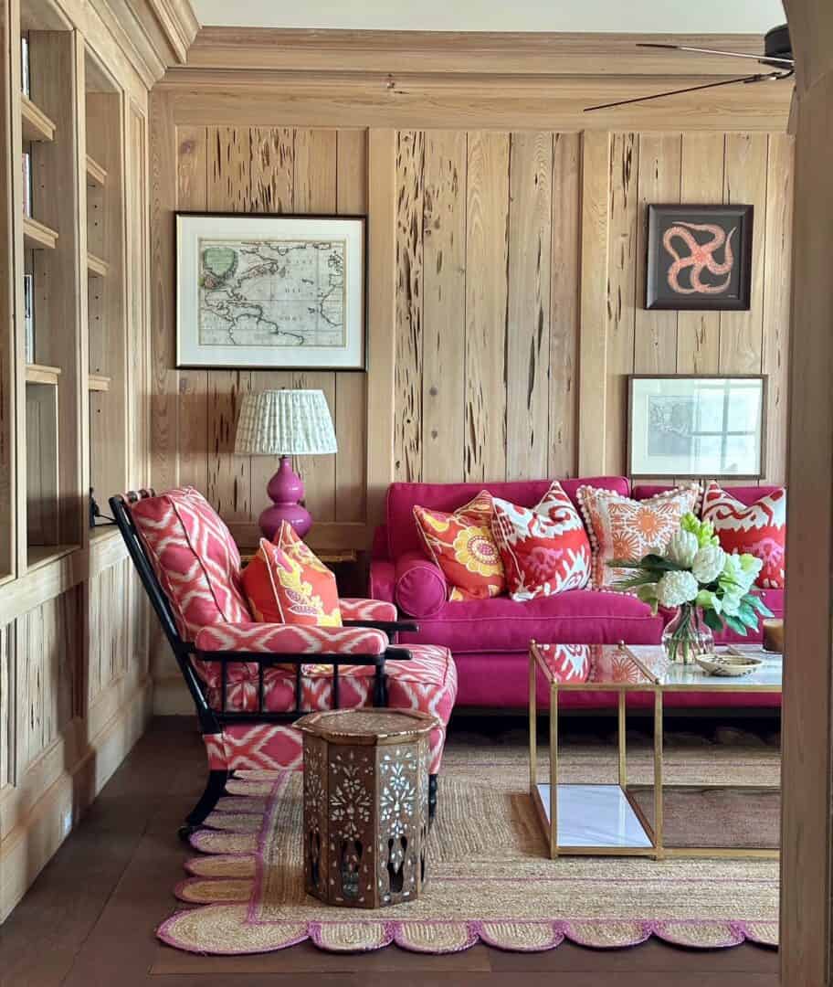 Cozy living room with pink sofa, patterned armchair, and wooden wall decor.
