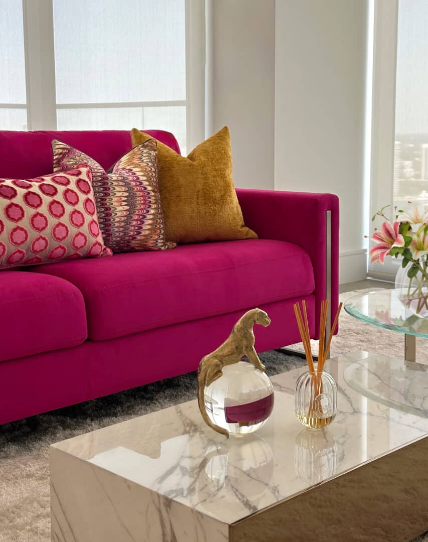 Modern living room with vibrant pink sofa and decorative pillows.