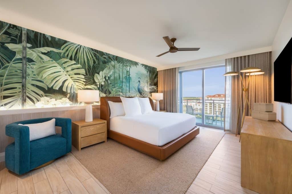 Luxurious hotel room with tropical mural, king bed, and balcony view of Nassau.