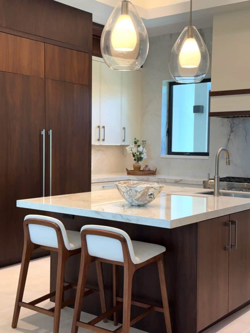 Modern kitchen with wooden cabinets, marble countertops, and pendant lighting.